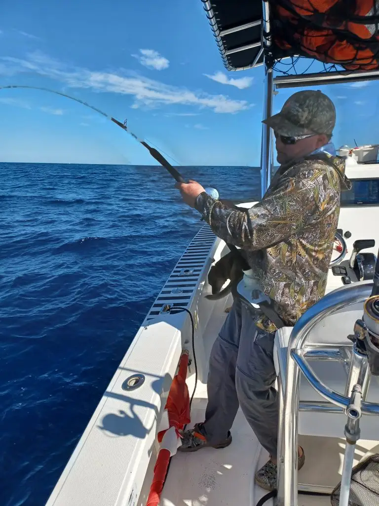 Lower Keys fishing charters guest reeling in hooked fish during exciting fishing adventure
