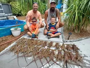 Two fathers and their children proudly displaying lobster catch during Lower Keys family charter adventure