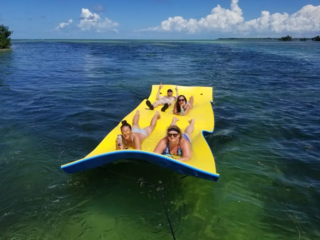 Four guests enjoying relaxing float time in crystal-clear Lower Keys waters during private charter