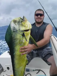 Charter guest proudly displaying fresh mahi mahi catch aboard vessel in Lower Keys waters