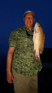 Charter guest displaying catch at night after successful Lower Keys fishing adventure