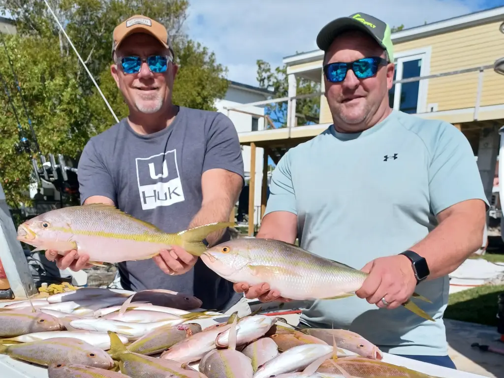 Two charter guests proudly displaying yellowtail snapper catch during Lower Keys charter rates fishing adventure