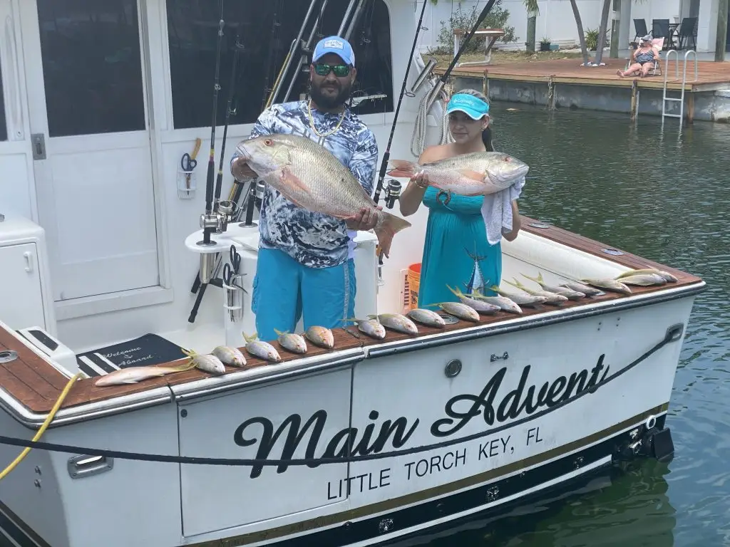 Two charter guests proudly displaying their catch aboard main adventure vessel during Lower Keys charter
